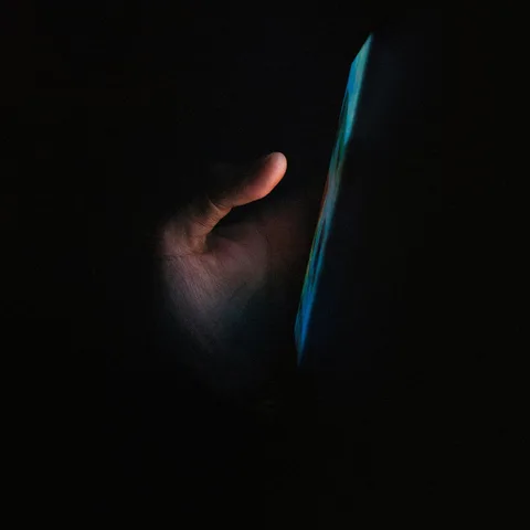 Hand holding a glowing phone in the dark
