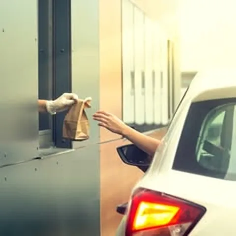 Driver receiving a fast food bag at a drive-thru window