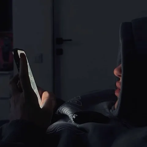 Person on a couch at night lit by their phone screen